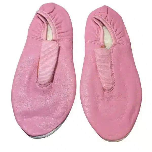 Close-up detail of the elastic strap and interior lining of a pink leather gymnastic slipper.